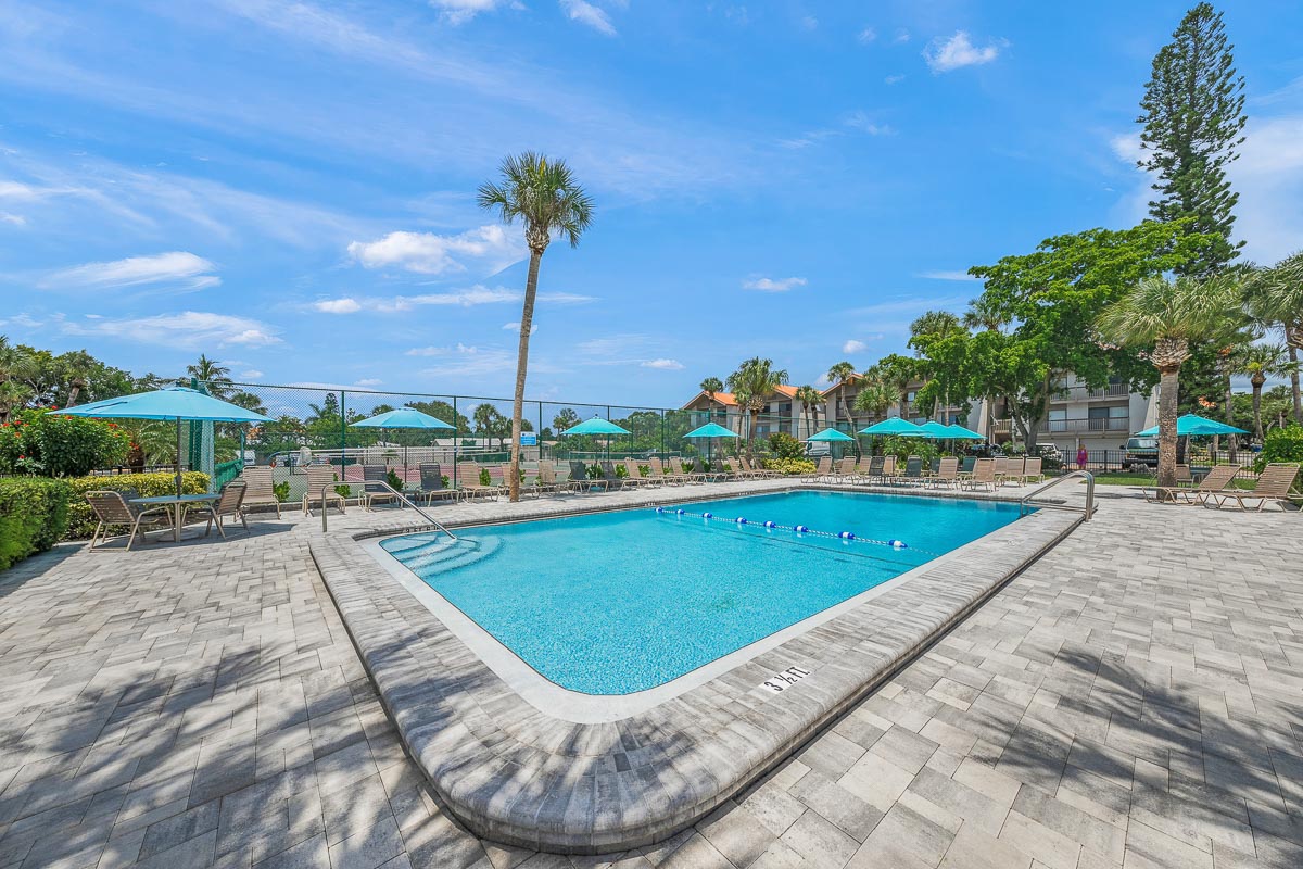 A swimming pool with lounge chairs and umbrellas on a sunny day.