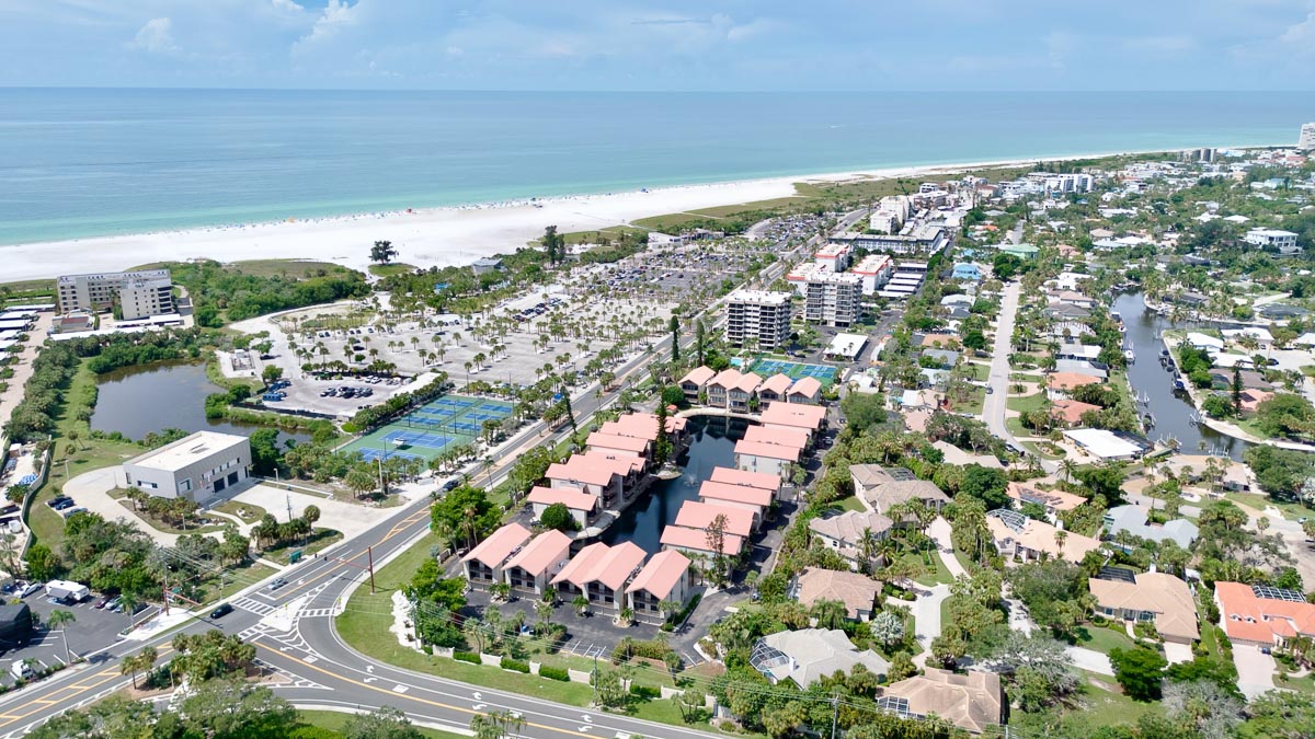 Aerial view of a beachfront property with buildings, parking, and ocean view.